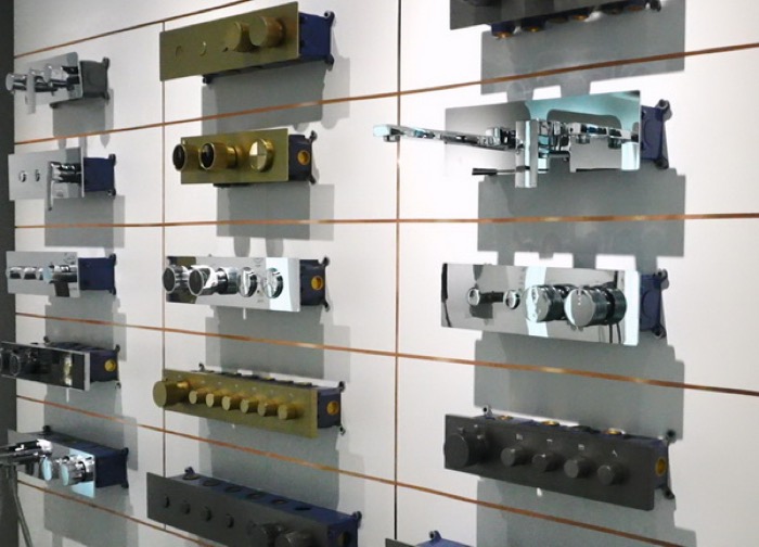 Concealed shower valve bodies displayed on a showroom wall board